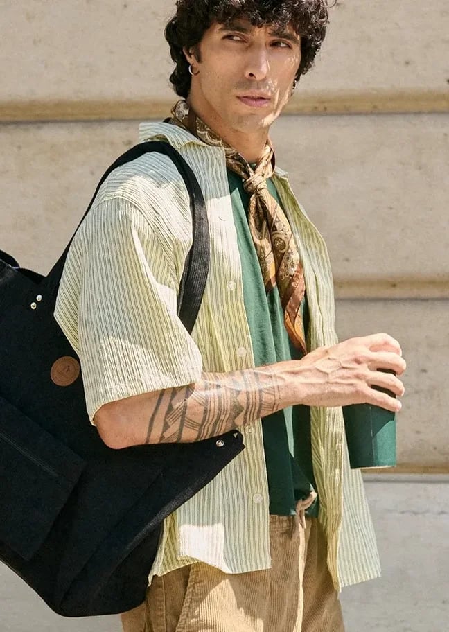 A man carrying a large black CABAIA tote bag in the city