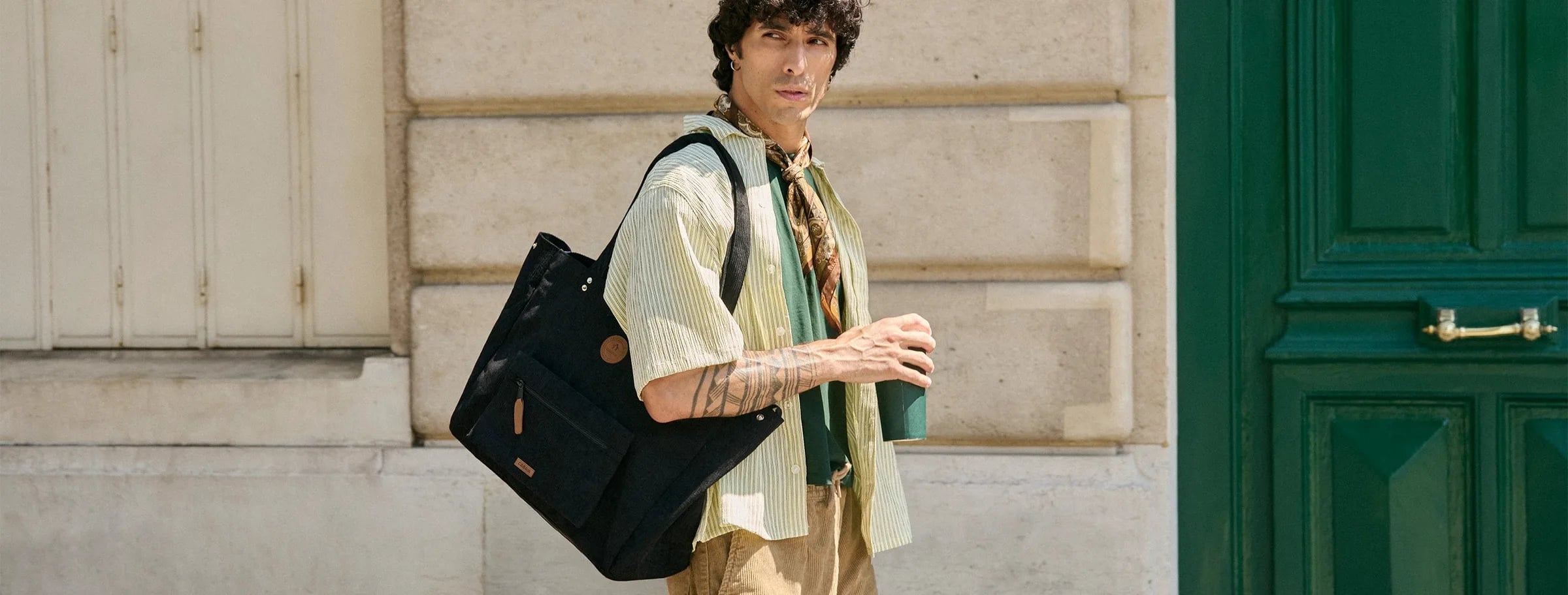 A man carrying a large black CABAIA tote bag in the city