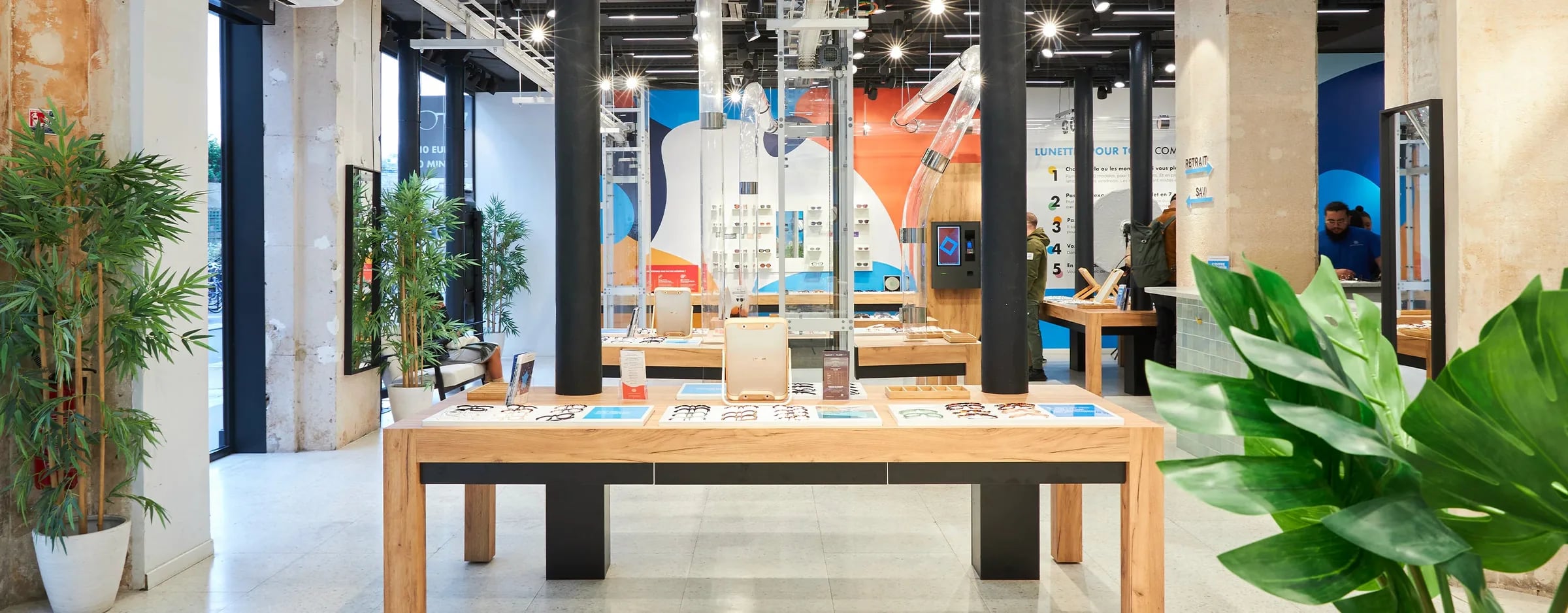 Inside the Lunettes Pour Tous flagship, with its frame tables and glass-walled workshop